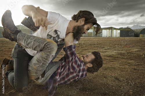 Two men with full beards fighting in abandoned landscape