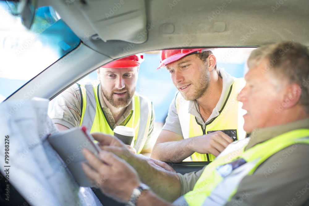 Builders discussing construction plan in car Builders discussing construction plan in car