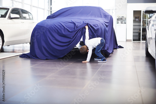 Boy at car dealer unveiling tarpaulin