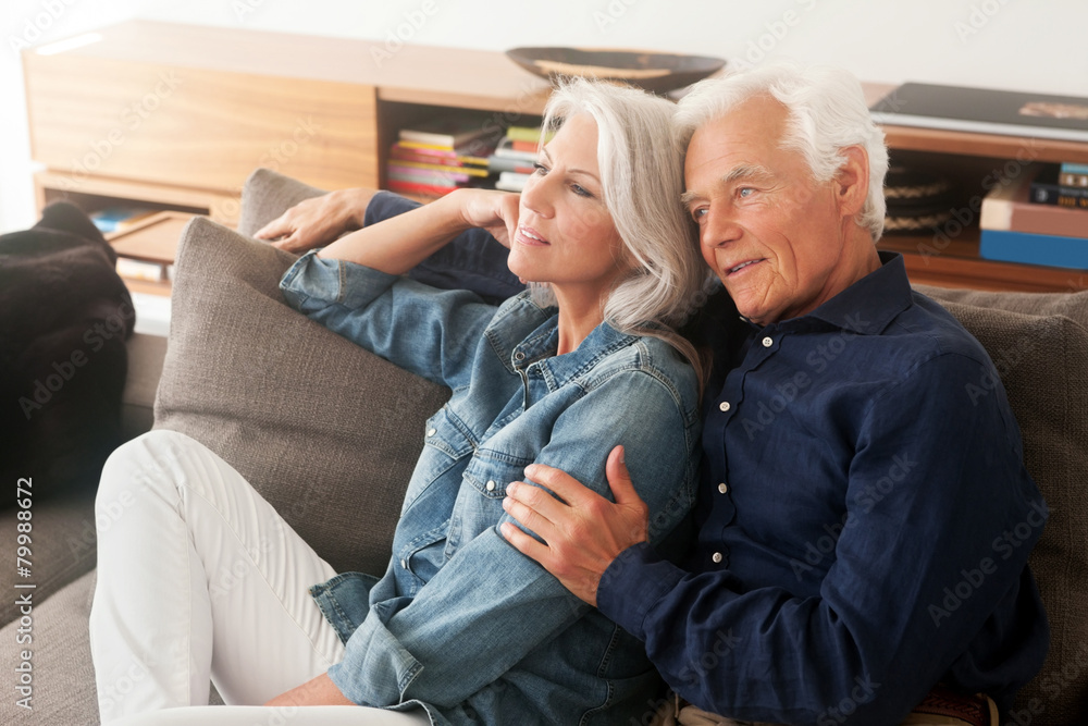Portrait of loving senior couple sitting side by side on the couch Portrait of loving senior couple sitting side by side on the couch