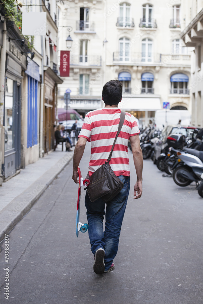 France, Paris, man with skateboard walking on a street France, Paris, man with skateboard walking on a street