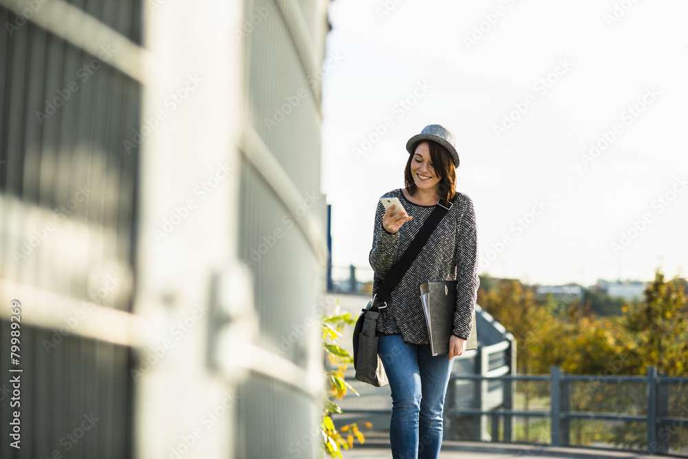 Smiling young woman with folder, bag and cell phone Smiling young woman with folder, bag and cell phone