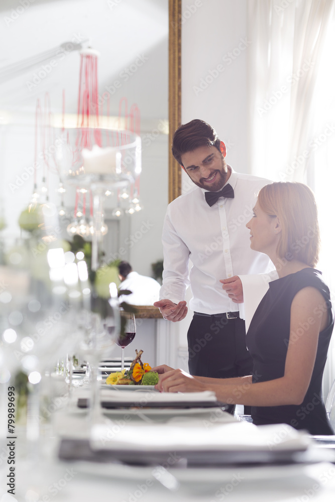 Waiter serving dinner to woman in elegant restaurant Waiter serving dinner to woman in elegant restaurant