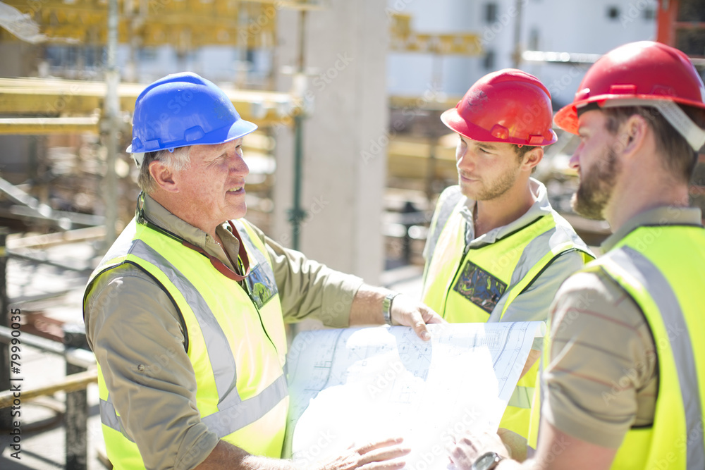 Construction workers discussing building plans in construction site Construction workers discussing building plans in construction site