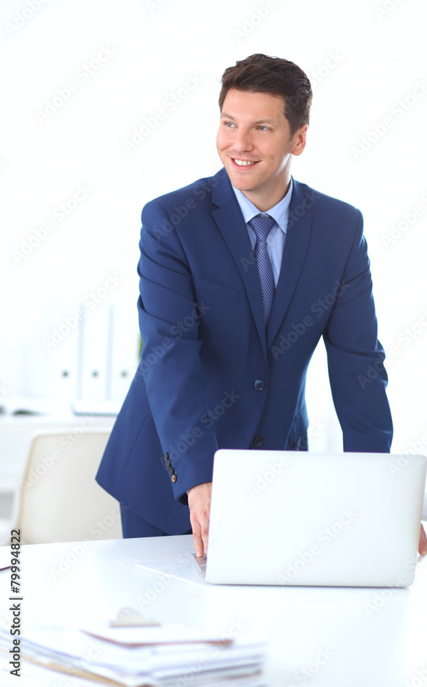Business man or manager standing against his desk at the office Business man or manager standing against his desk at the office