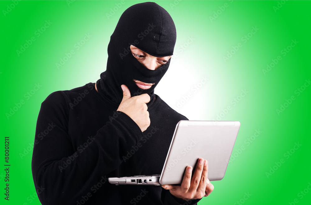 Hacker with computer wearing balaclava Hacker with computer wearing balaclava