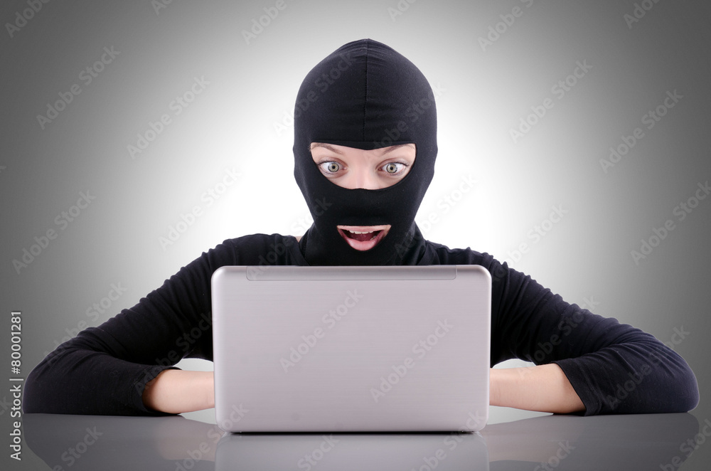 Hacker with computer wearing balaclava Hacker with computer wearing balaclava