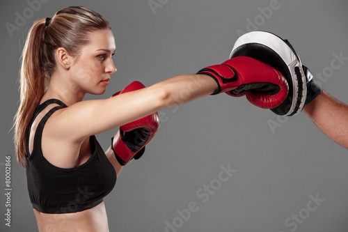 beautiful woman is boxing on gray background