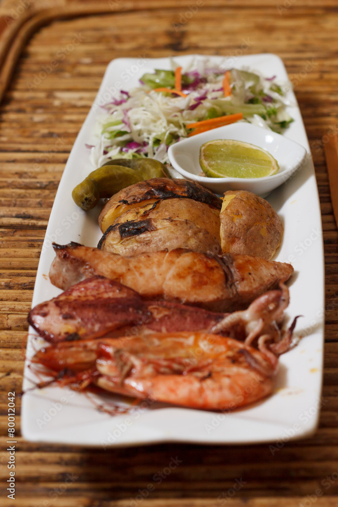 Seafood mix barbecue with salad on plate on bamboo table