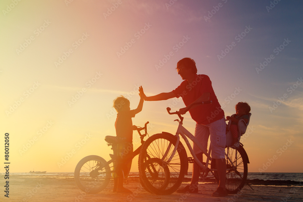 Obraz premium Biker family silhouette, father with two kids on bikes
