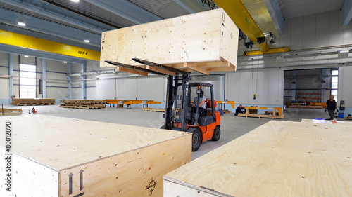 Gabelstapler hebt Holzkiste mit Waren in Industriehalle photo