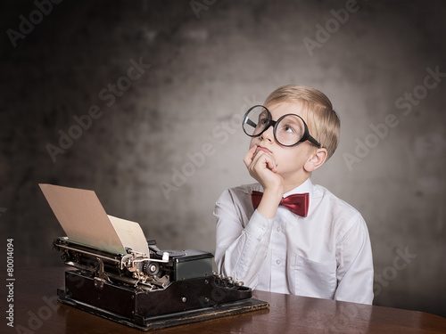 Dreaming boy with old typewriter. Retro style portrait