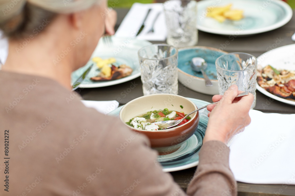 close up of woman eating soup in summer garden