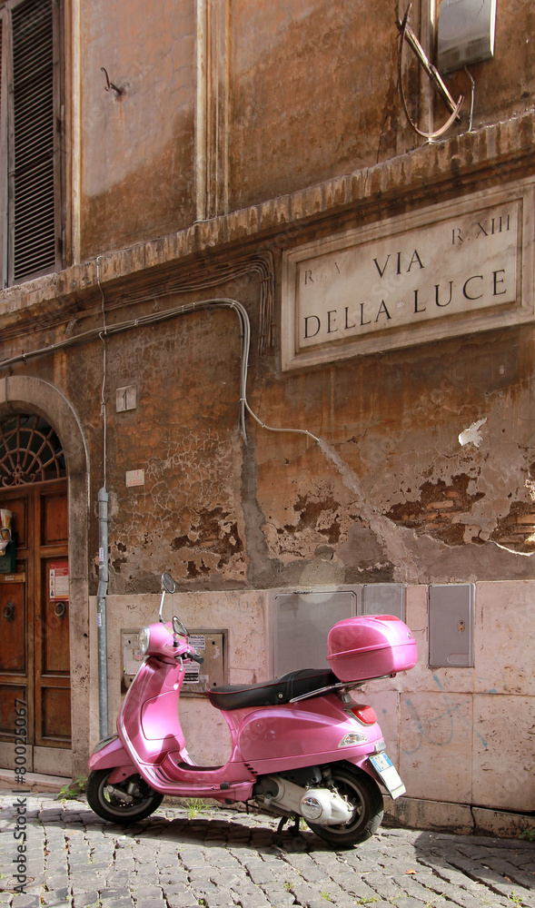 Fototapeta premium Scooter rose dans une petite rue pavée romaine - Italie