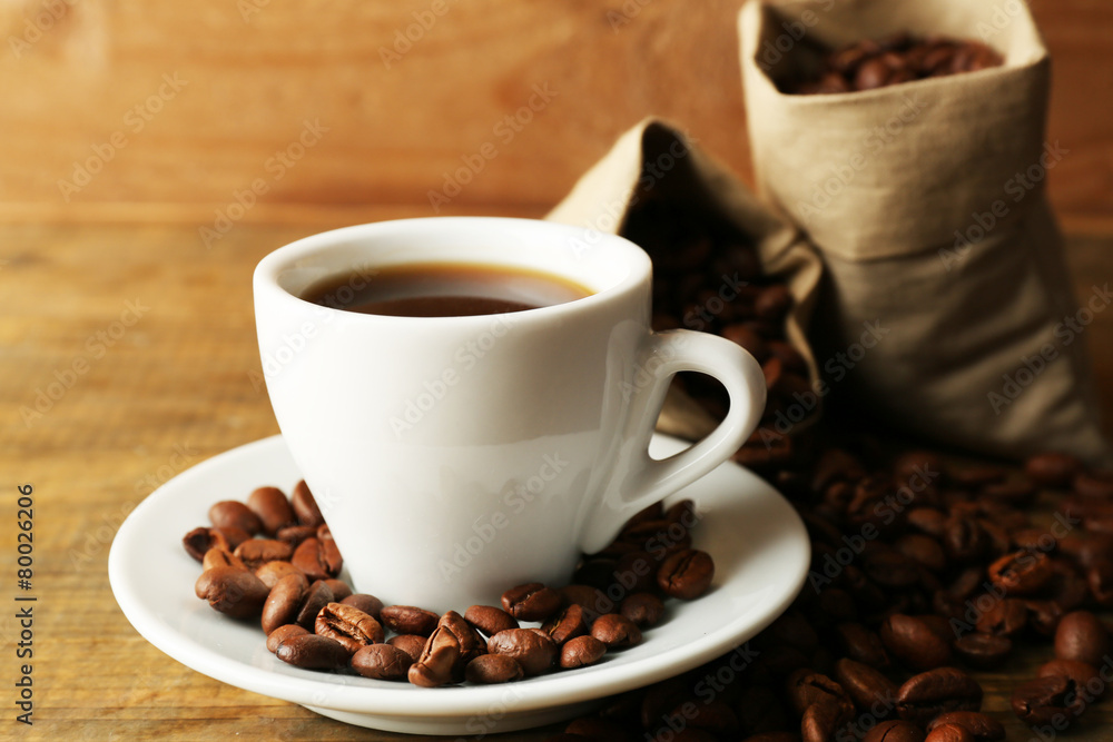 Obraz premium Cup of coffee with beans on rustic wooden background