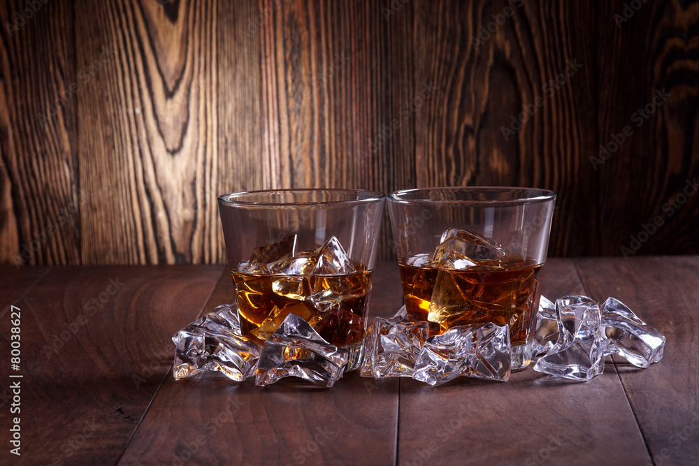 Glasses of whiskey on wood background