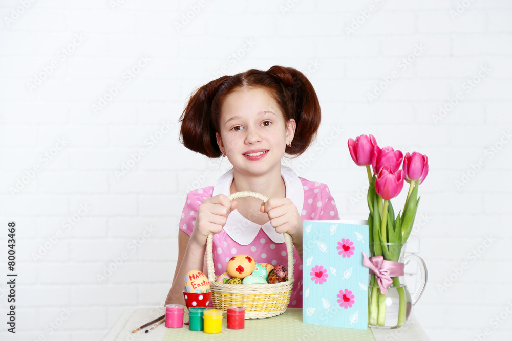 Cute girl decorates Easter eggs, on light background Cute girl decorates Easter eggs, on light background