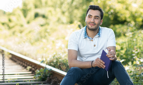 Handsome young man sitting and holding book