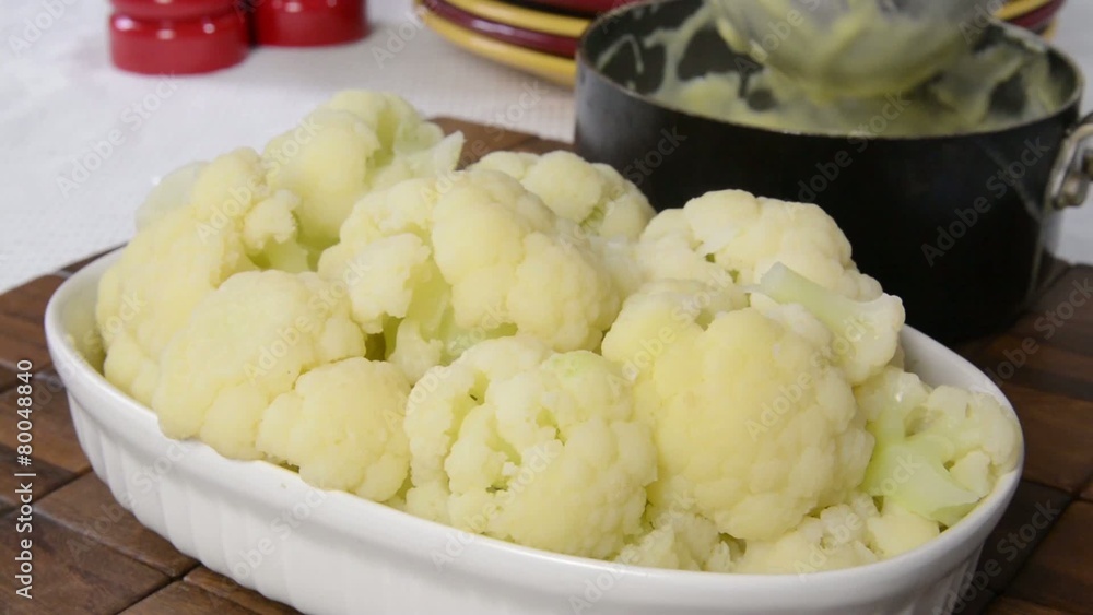 Spooning hollandaise sauce onto fresh steamed cauliflower Spooning hollandaise sauce onto fresh steamed cauliflower