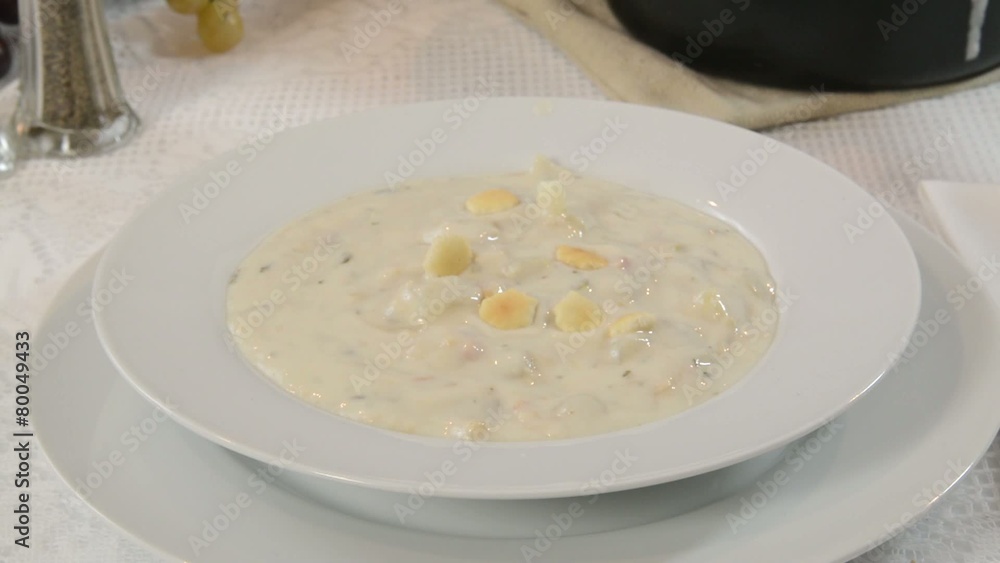 Sprinkling saltine crackers into a bowl of clam chowder Sprinkling saltine crackers into a bowl of clam chowder