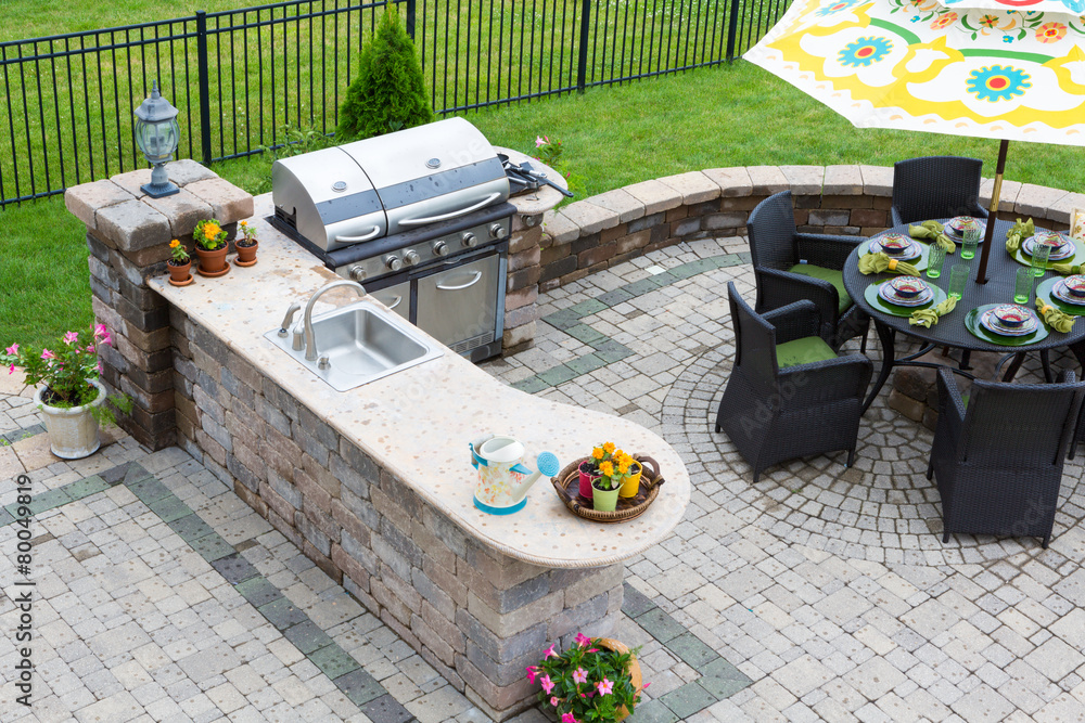 Outdoor kitchen and dining table on a paved patio - obrazy, fototapety, plakaty 