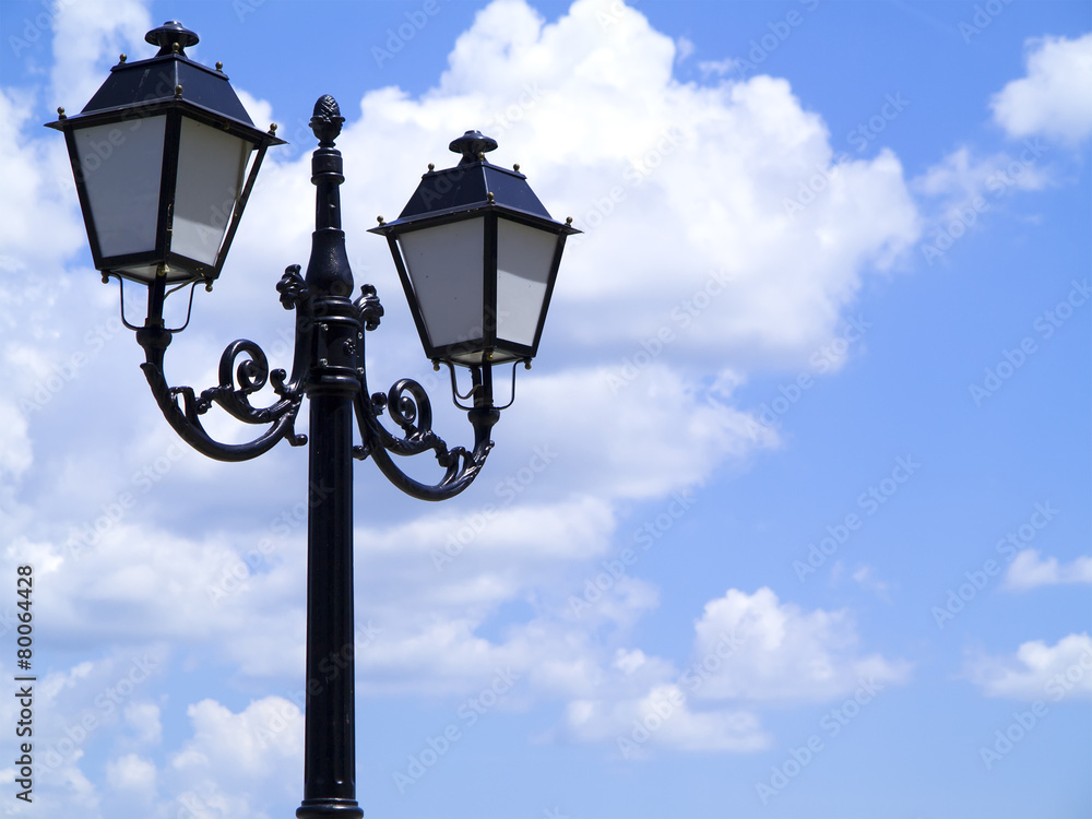 Old street decorated lamppost against cloudy blue sky