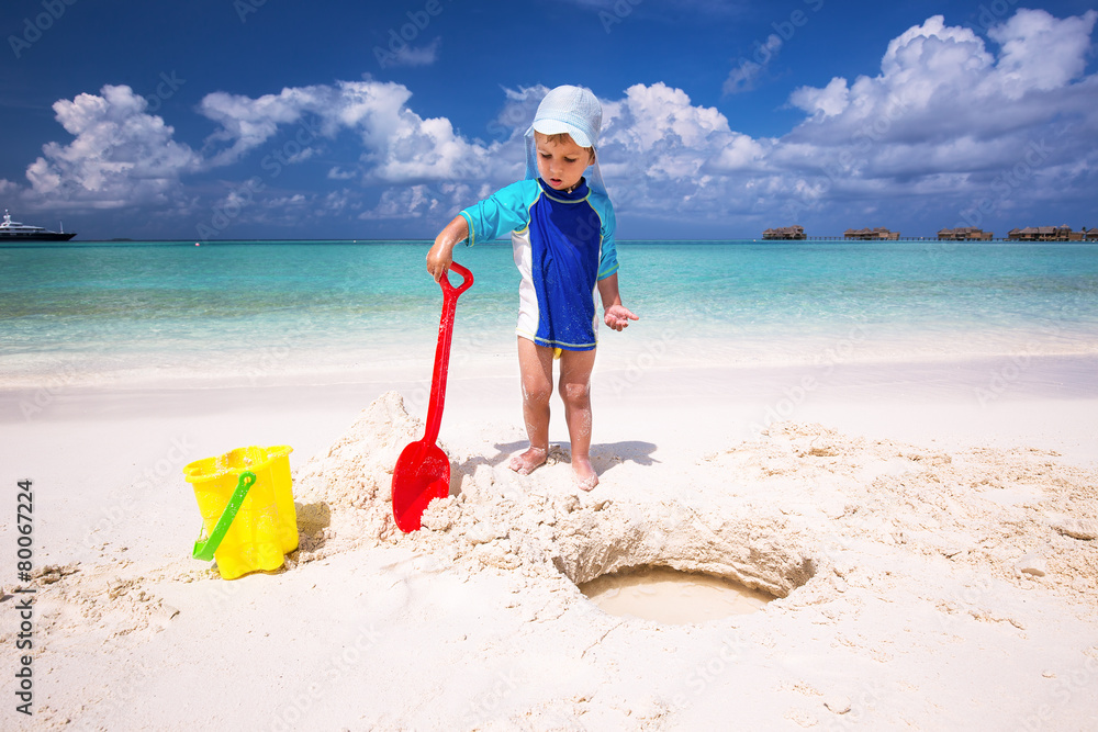 Little boy having fun on the beach while building a sand castle Little boy having fun on the beach while building a sand castle