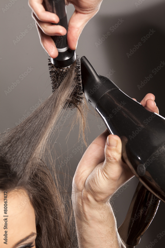 Naklejka premium hairdresser doing his client hair with a hair drier and comb