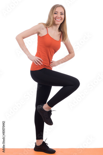 Smiling woman in sportswear training legs on a mat.