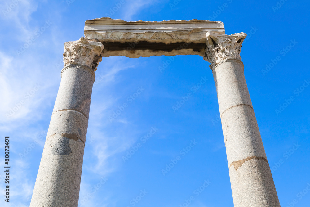 Two columns and portico fragment on blue sky background