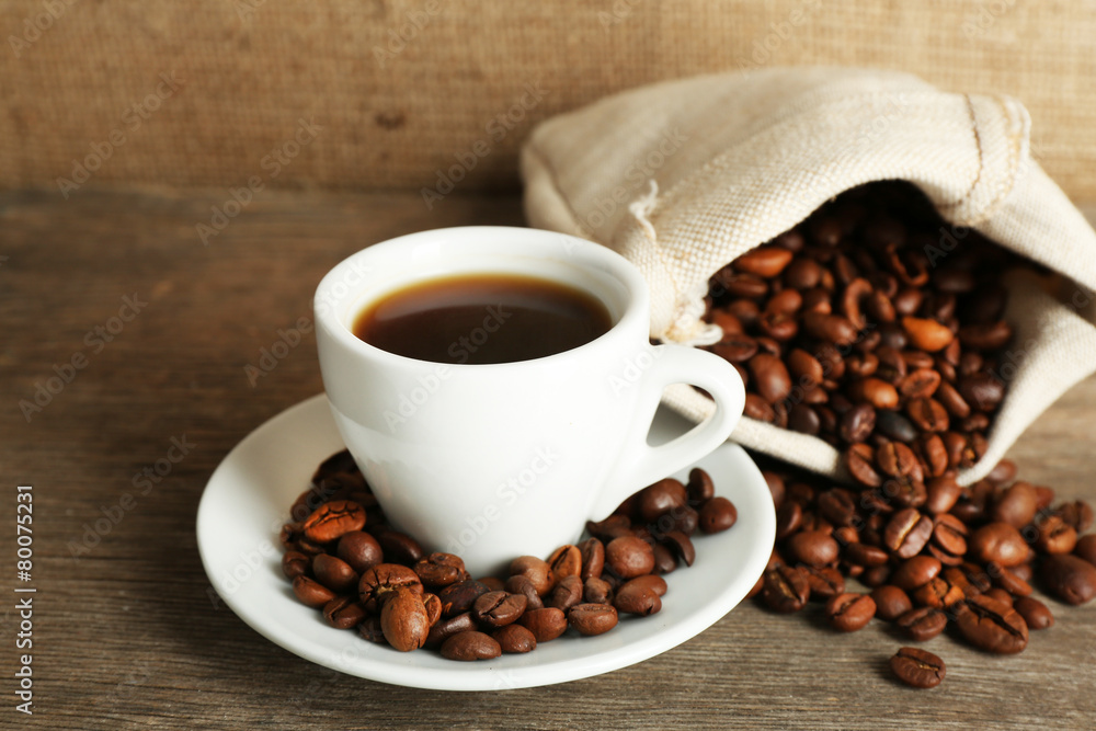 Fototapeta premium Cup of coffee with beans on rustic wooden background