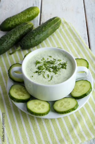 Cucumber soup in bowl on color wooden table background