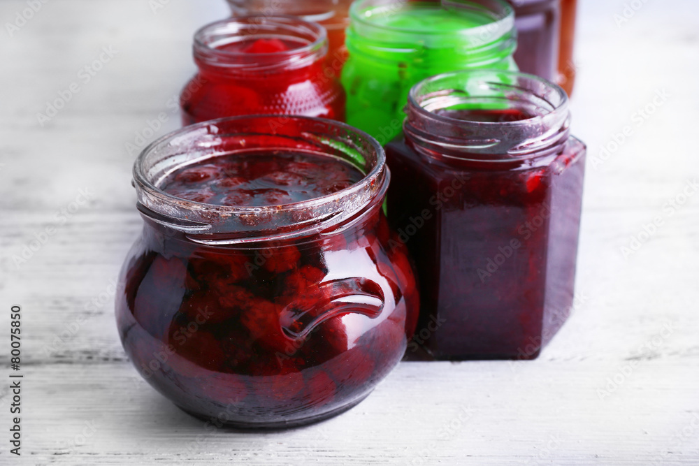 Homemade jars of fruits jam on color wooden planks background Homemade jars of fruits jam on color wooden planks background