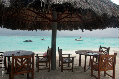 Chairs and tables under big umbrella at beach © Dane Mo