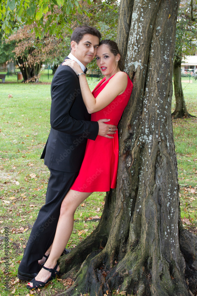 Couple kissing next to tree in garden