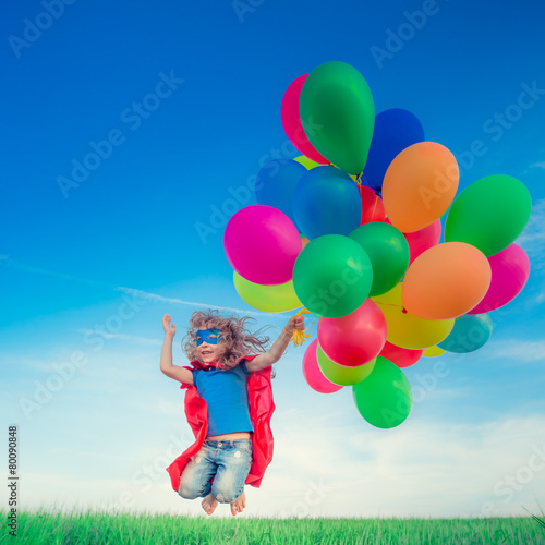 Superhero with toy balloons in spring field