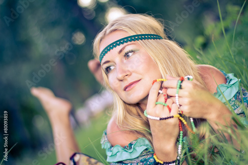 Pensive thoughtful hippie girl is lying on a grass