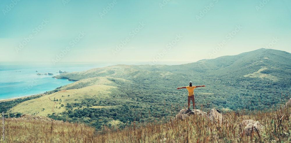 Traveler man standing on peak of mountain near the sea