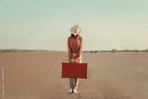 Traveler woman standing with suitcase on road