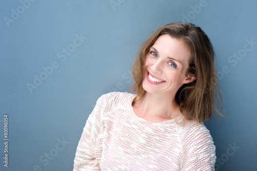 Attractive smiling mid adult woman on blue background © mimagephotos