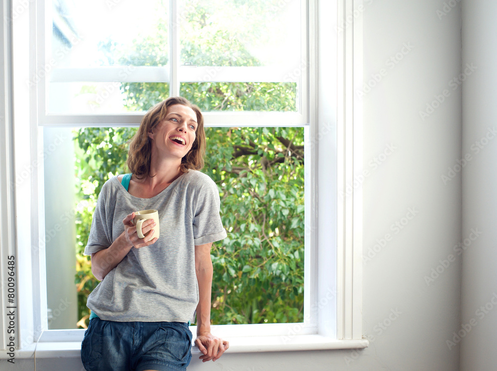 Happy woman laughing with a cup of coffee at home