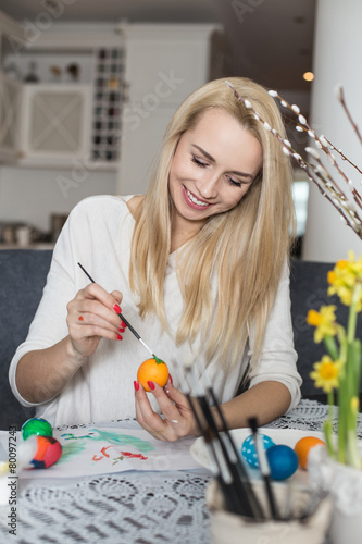 Beautiful young woman painting easter eggs