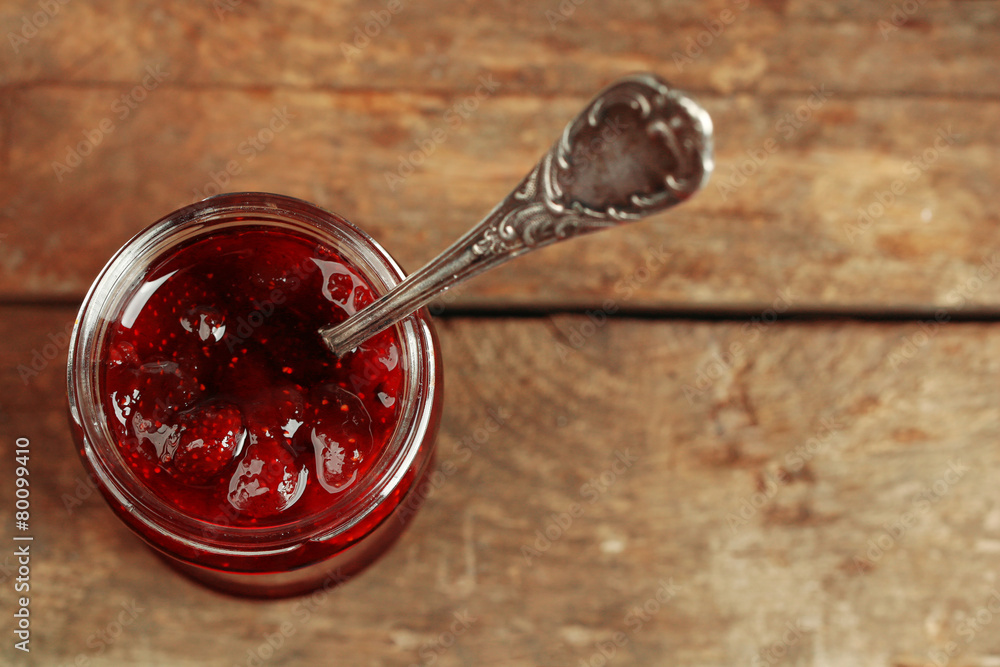 Jar of strawberry jam with spoon on wooden background Jar of strawberry jam with spoon on wooden background