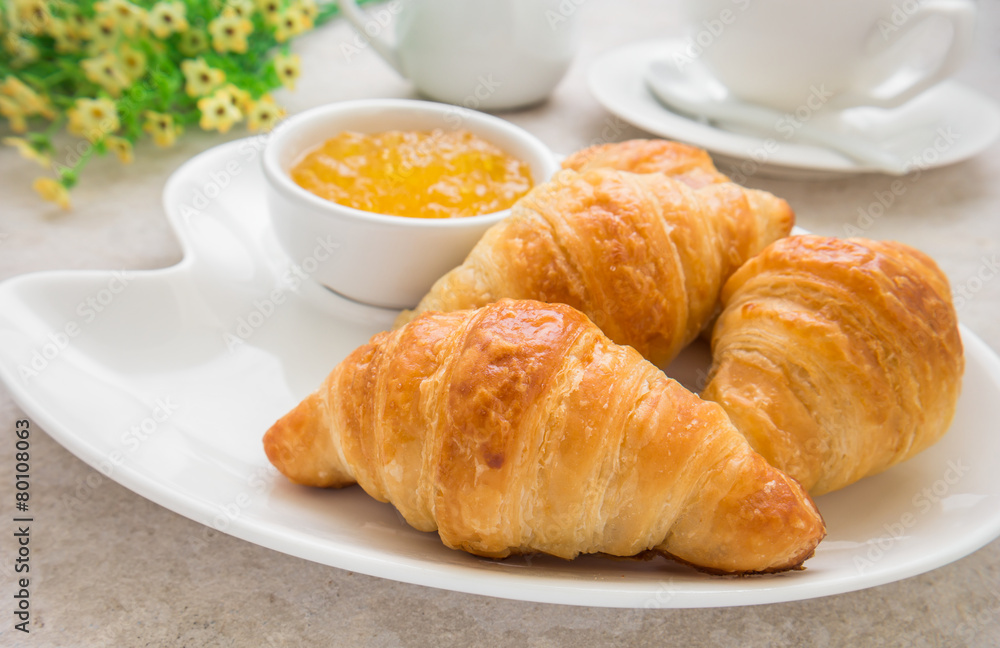 Croissants with jam on plate and coffee cup