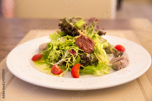 Green salad with chicken meat, dried tomatoes and pine nuts