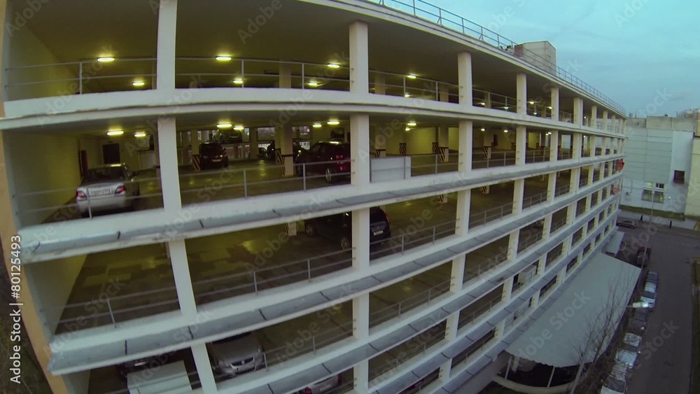 Automobiles stand in multistory garage at autumn evening Automobiles stand in multistory garage at autumn evening