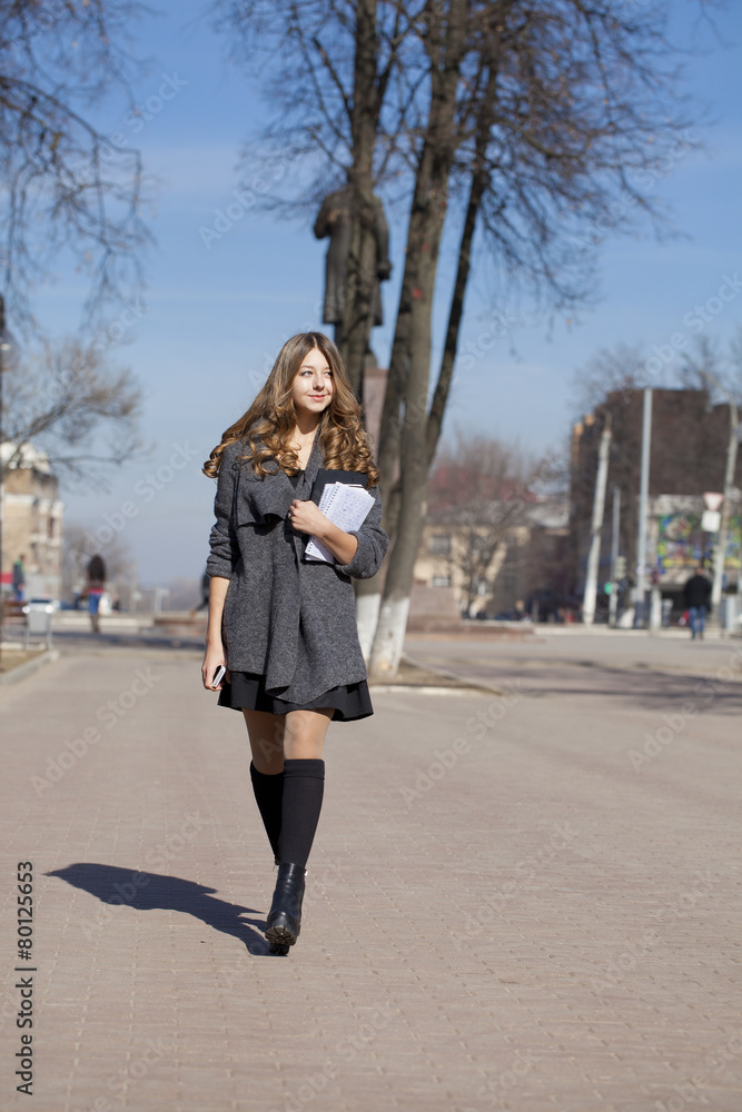 Schoolgirl walking on spring sunny street