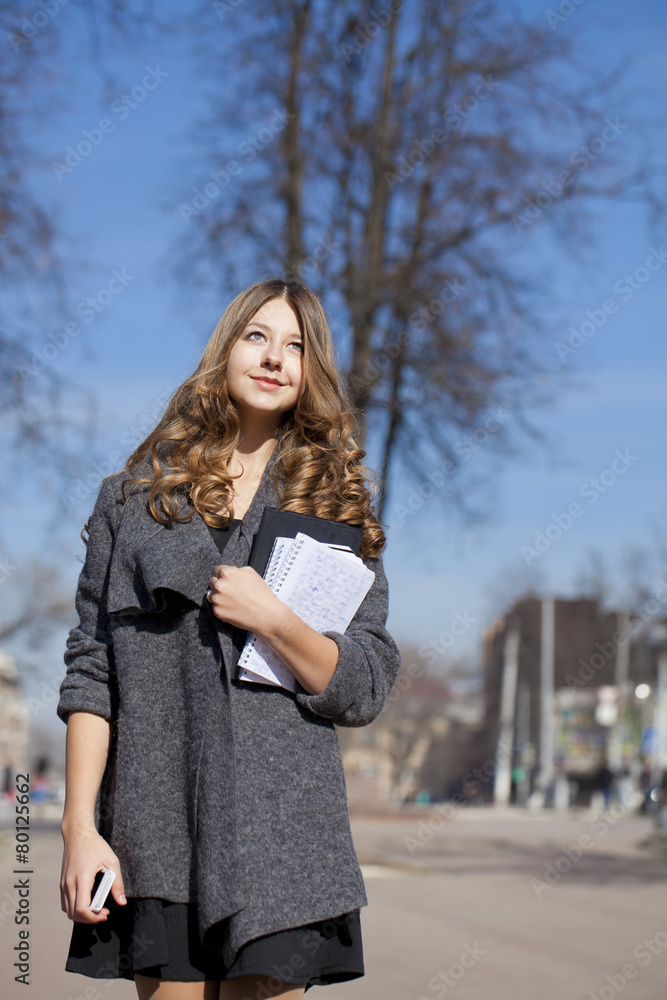 Schoolgirl walking on spring sunny street