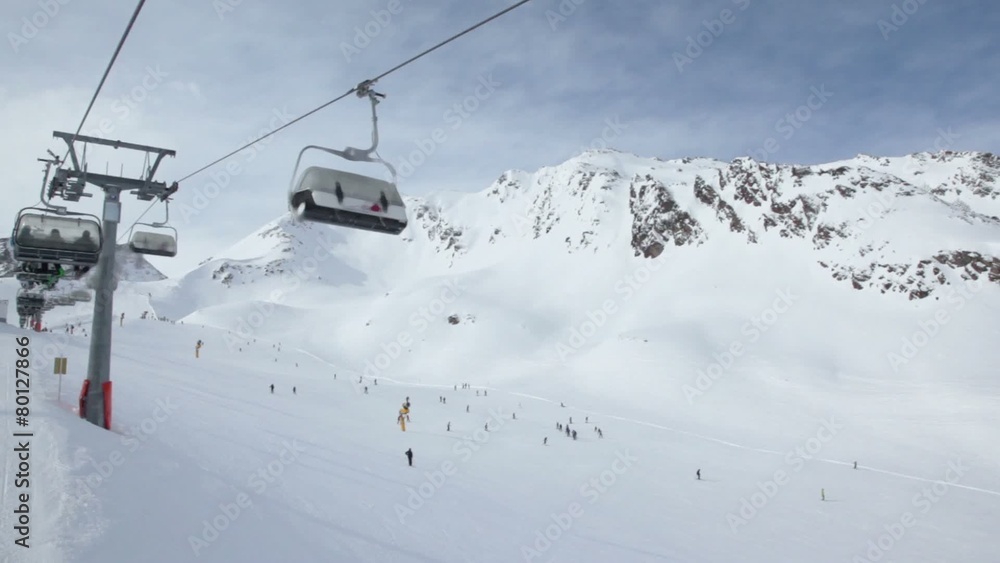Ski chair-lift with skiers in snow-capped mountains Ski chair-lift with skiers in snow-capped mountains