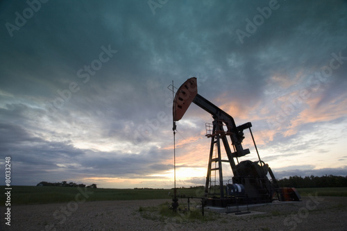 An oil derrick, a well head pump arm with frame, silhouetted against the evening sky. Oil business.  photo